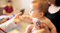 Doctor using a stethoscope to check a baby.